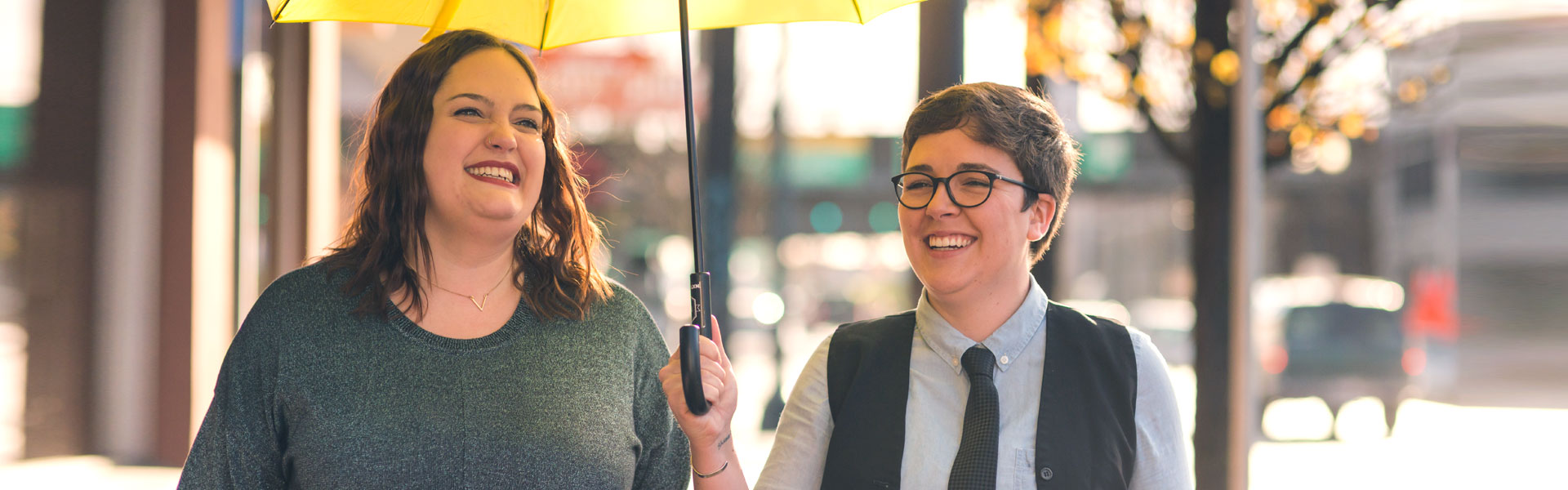 women smiling under yellow umbrella